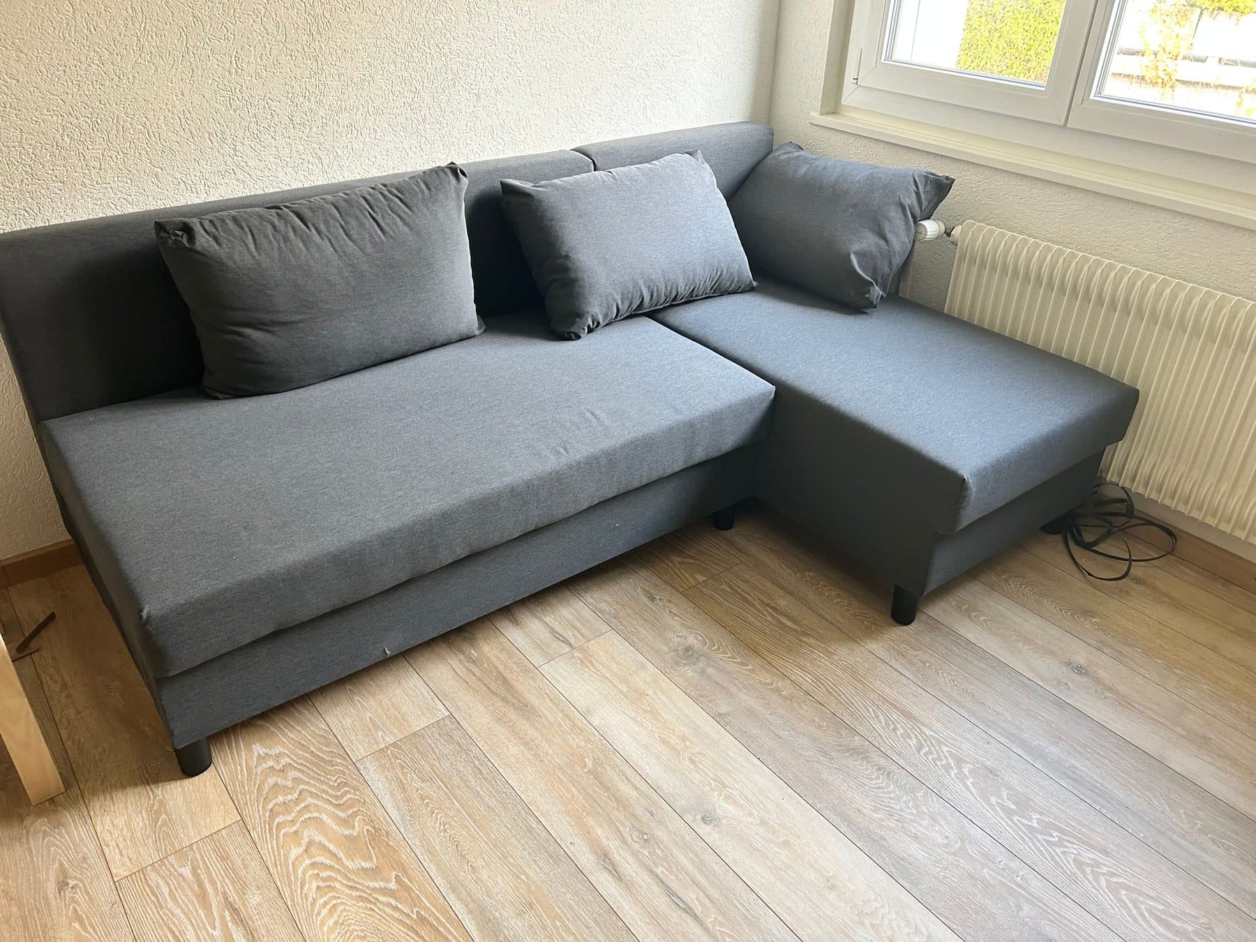 Canapé d'angle gris dans un séjour lumineux après nettoyage