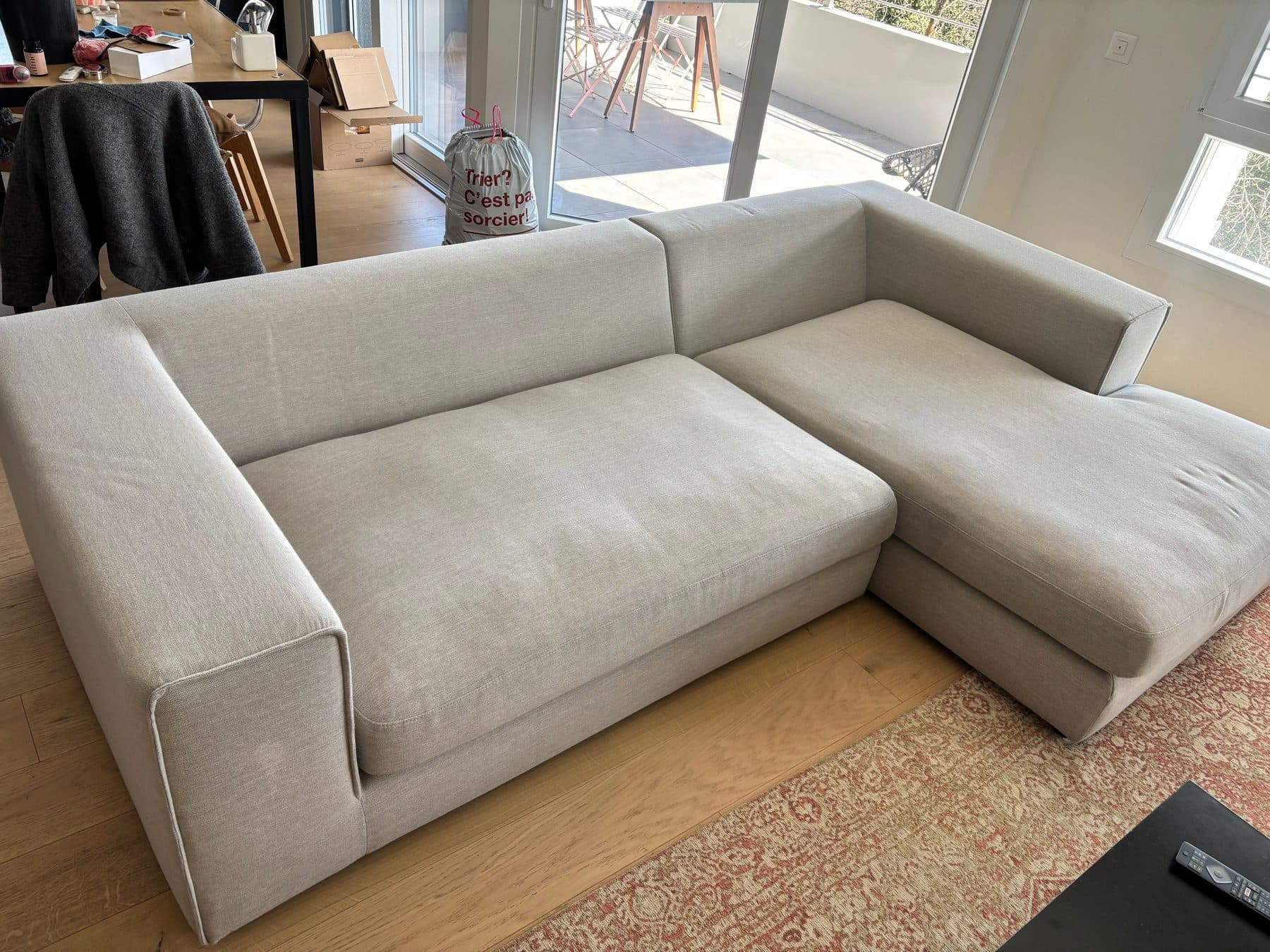 Grand canapé d'angle en tissu clair dans un séjour, nettoyé en profondeur